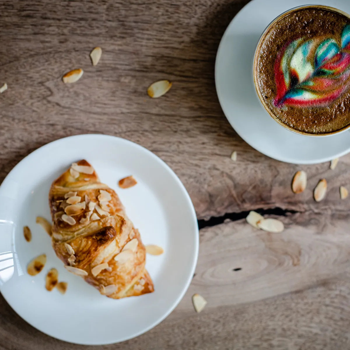 Café et croissant aux amandes sur une table en bois