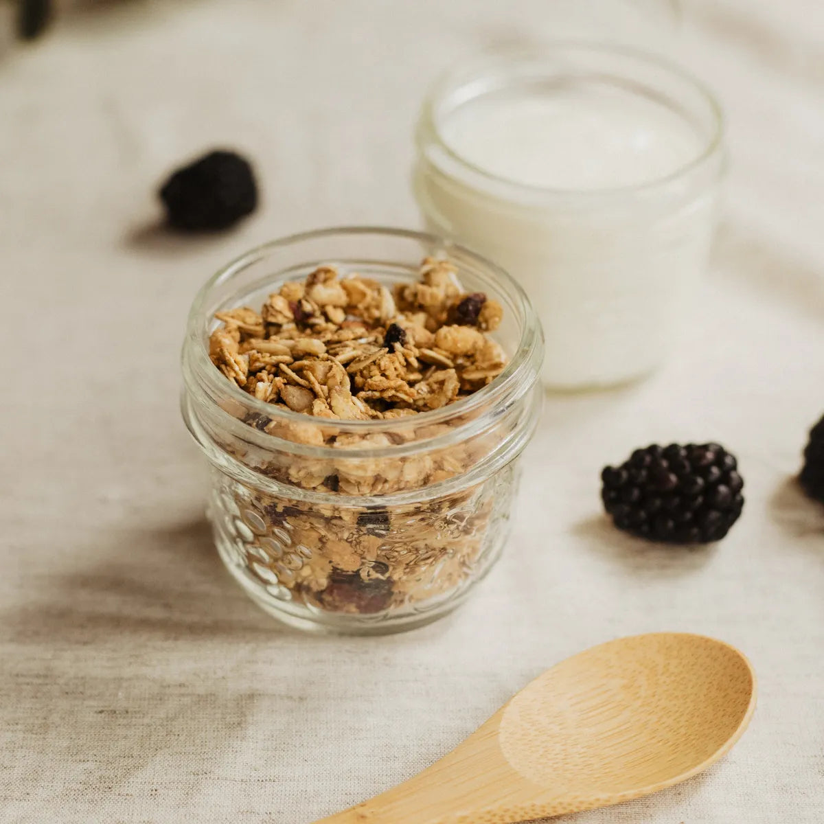 Pots de granola et de yaourt sur une nappe claire